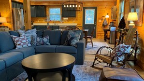 A cozy cabin interior with a living room, dining area, and kitchen. - Play & Stay near State Parks & Seven Springs (Champion)