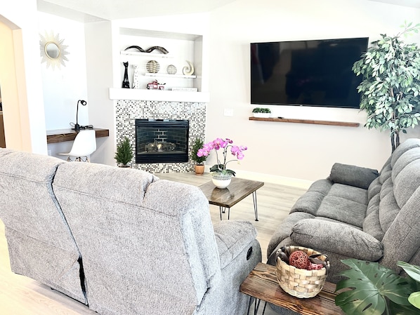 A modern living room with a fireplace, a flat-screen TV, and comfortable seating.