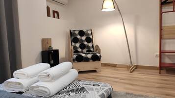 A room with a bed, a polka-dotted chair, a standing lamp, and a red shelf.