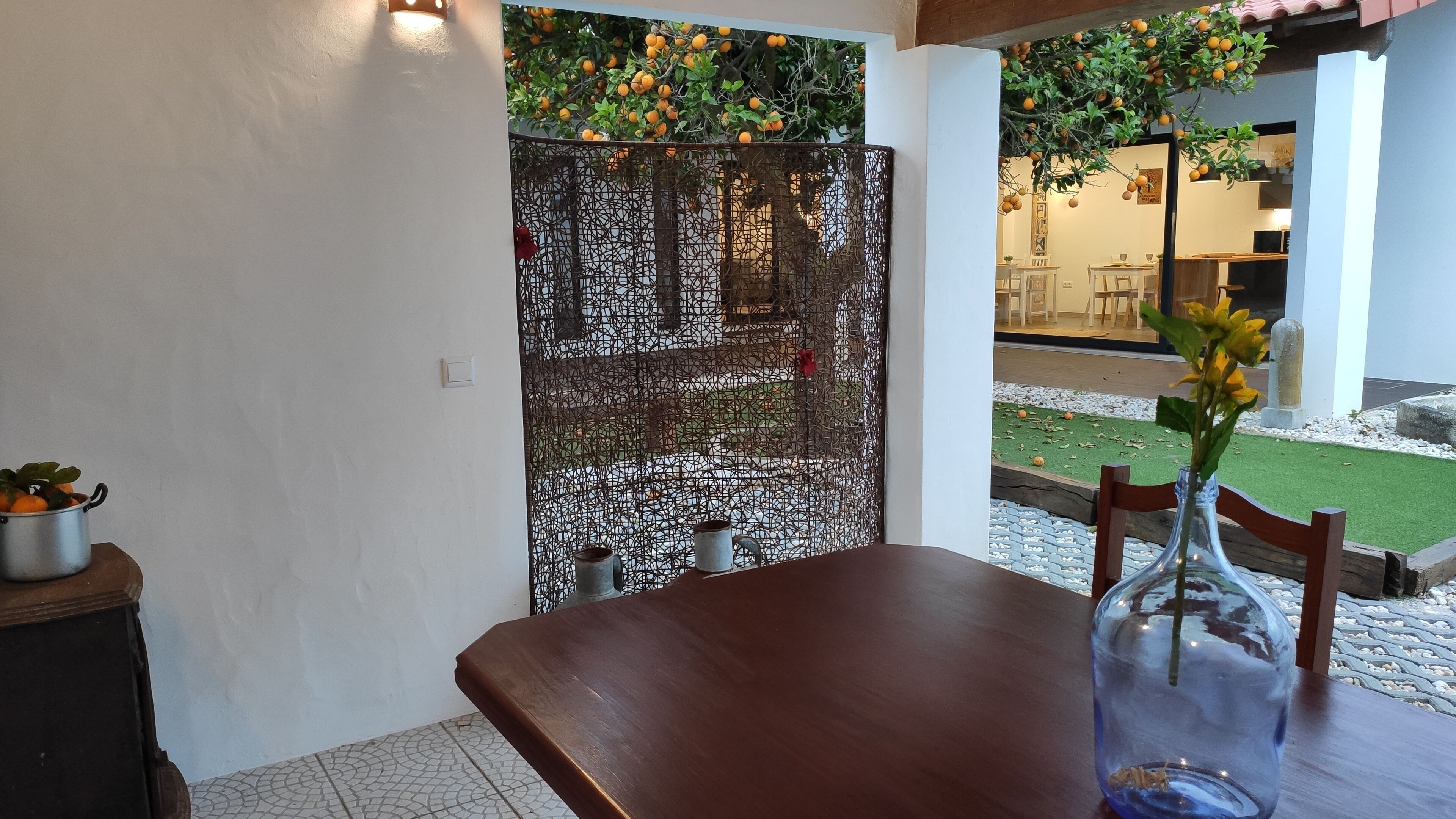 A dining area with a wooden table, a vase with flowers, and a decorative metal screen.