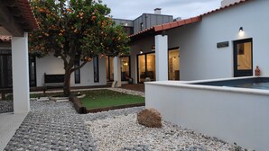 A modern outdoor area with a swimming pool, a tree with oranges, and a patio with a stone pathway. - Laranjeira das Loiras (Obidos)