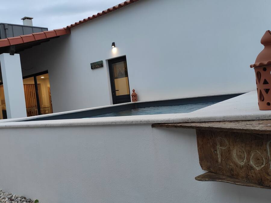 Ein modernes Gebäude mit weißer Fassade, einem kleinen Pool und einem Holzschild mit der Aufschrift 'Fool'.