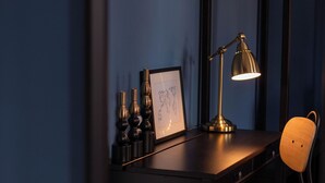 Ein dunkler Holztisch mit Lampe, Stuhl und gerahmtem Bild.