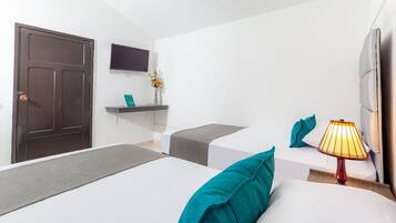 Una habitación de hotel moderna con cama, mesita de noche, lámpara y un televisor de pantalla plana montado en la pared.