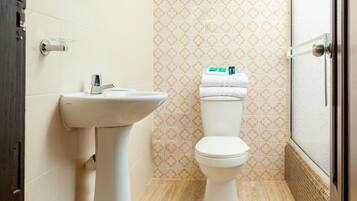 A bathroom with a white sink, toilet, and patterned tile walls.