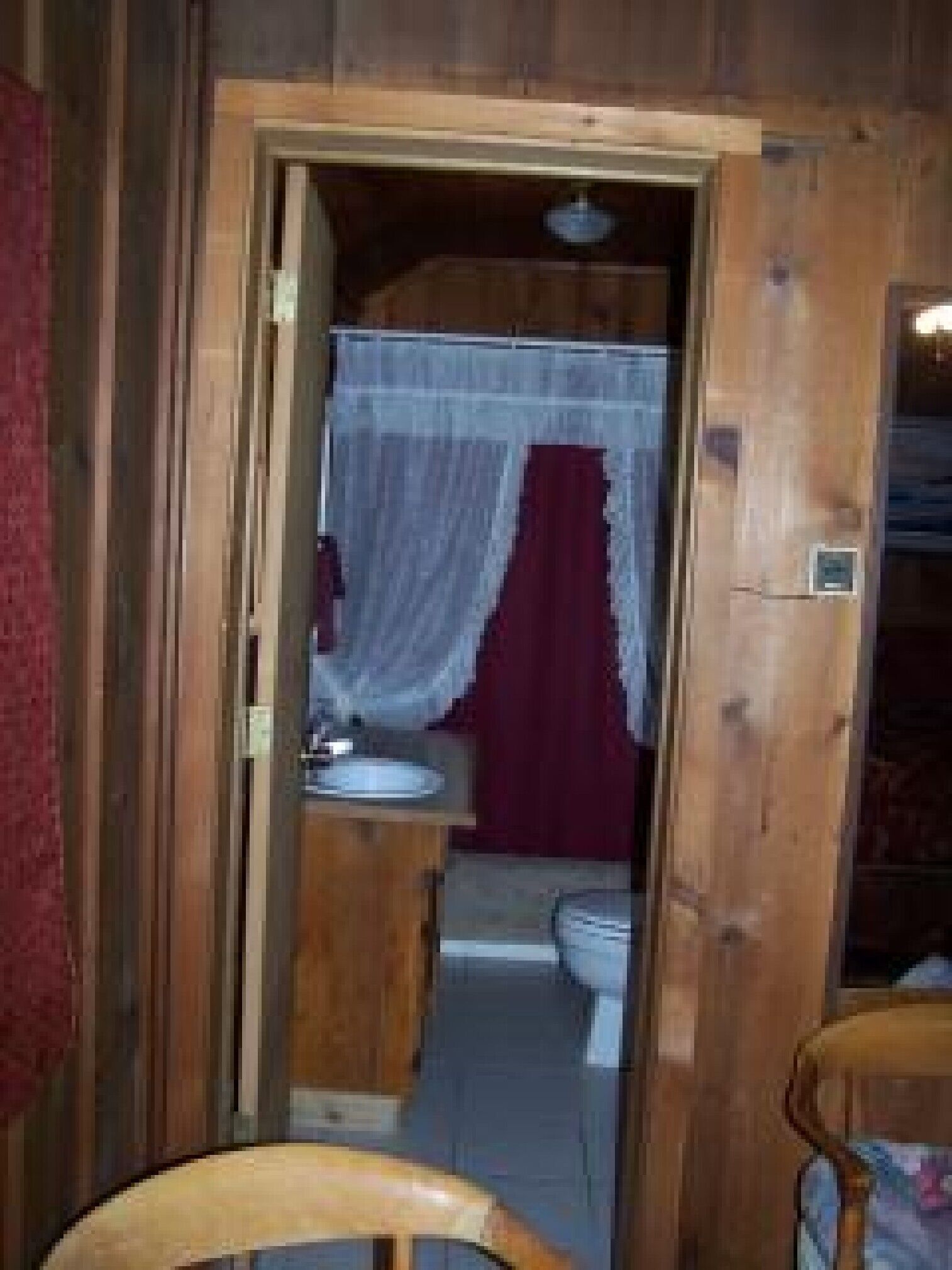 Interior de uma cabana de madeira, com banheiro visível, incluindo pia, vaso sanitário e área de chuveiro.