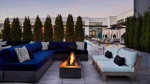 A rooftop lounge area with a fire feature, two sofas, and a lounge chair.