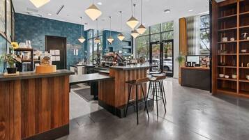 A modern bar area with a wooden counter, bar stools, pendant lighting, and a view of the street outside.