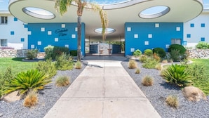 A modern building with a unique architectural design, featuring circular cutouts on the facade, a central entrance, and a well-maintained garden with various plants. - HeatedPool, Upscale in OldTown Scottsdale (Scottsdale)