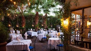An outdoor dining area with tables set for a meal, surrounded by greenery and palm trees. - HeatedPool, Upscale in OldTown Scottsdale (Scottsdale)