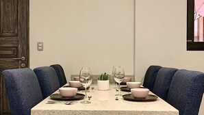 Une table de salle à manger rectangulaire à la surface mouchetée, entourée de six chaises bleues recouvertes de tissu.