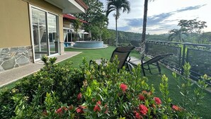 Eine Terrasse mit Pool, Sitzgelegenheiten im Freien und üppiger Bepflanzung.
