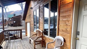 Eine Holzhütte mit Veranda, zwei Holzstühlen und einem weißen Kunststoffstuhl.