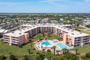 Stunning hotel with a central courtyard and swimming pool, surrounded by lush greenery and a residential view.