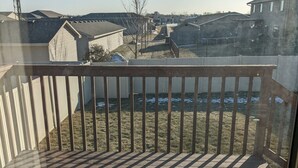 A wooden deck with a railing, a clear sky, and residential buildings in the background. - Cozy ranch style house in a quiet neighborhood (Sioux Falls)