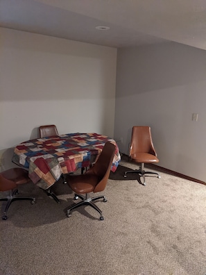 A conference room with a round table covered by a colorful quilt, two brown leather chairs, and carpeted flooring.