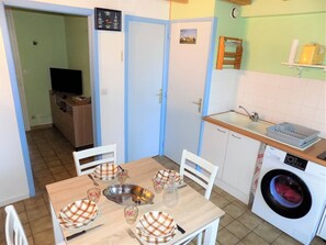 Une cuisine compacte équipée d’un lave-linge, d’un évier et d’un coin repas avec une table dressée pour quatre personnes.