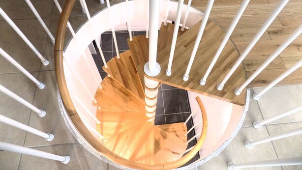 A spiral staircase with white railings and wooden steps.