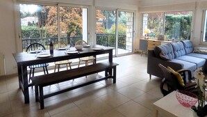 A spacious living room with a dining area, large windows, and a balcony.