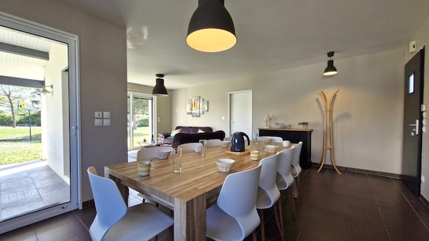 Un comedor moderno con una mesa de madera, sillas blancas e iluminación colgante.