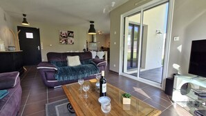Una sala de estar moderna con un sofá, una mesa baja con copas de vino y un televisor.