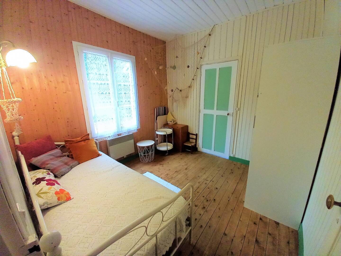 A cozy room with a bed, a small table, a chair, and a window with curtains.