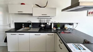 A modern kitchen with white cabinets, a black countertop, and a stainless steel sink. - Saint Palais sur Mer - VERY NICE RECENT HOUSE - near the GOLF (ST PALAIS SUR MER)