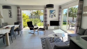 A modern living room with a dining area, a TV, and a large sliding glass door leading to a patio. - Saint Palais sur Mer - VERY NICE RECENT HOUSE - near the GOLF (ST PALAIS SUR MER)