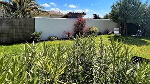 A residential garden with a white wall, palm trees, and a house with a tiled roof. - Saint Palais sur Mer - VERY NICE RECENT HOUSE - near the GOLF (ST PALAIS SUR MER)