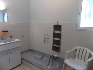Un bagno con una vasca, un lavandino, uno specchio e una sedia bianca.