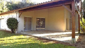 Une maison de plain-pied avec un patio couvert, un petit jardin et un garage.