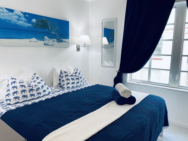 A neatly made bed with a blue and white patterned bedspread, a white pillow with elephant prints, and a rolled towel on the bed. - Lovely renovated 1 bedroom on ocean drive jacuzzi (Miami Beach)