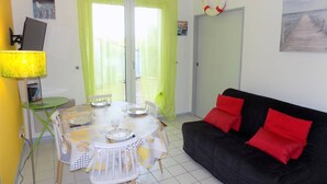 Ein Zimmer mit Esstisch, gedecktem für zwei Personen, einer schwarzen Couch mit roten Kissen und einer Rettungsboje als Wanddeko.