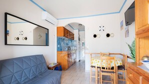 A compact living space with a sofa, a dining table with chairs, a kitchen area, and a mirrored wall. - AS21387-Studio cabin and private parking 200m sea (LE GRAU DU ROI)