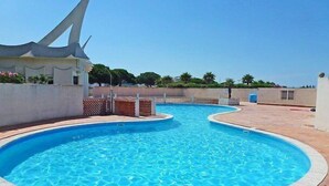 Una piscina con bordo curvo, circondata da un solarium piastrellato.