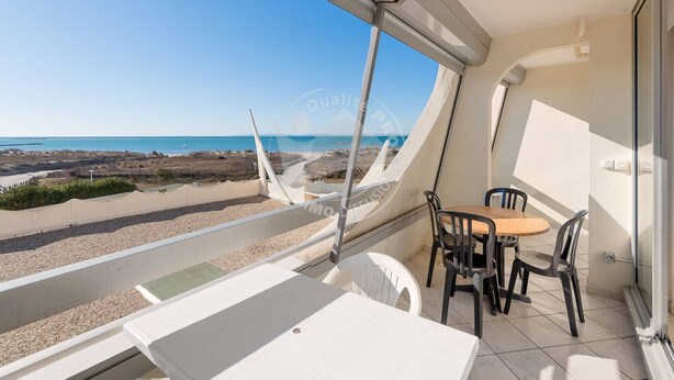 Un balcone con tavolo e sedie, vista sulla spiaggia e sul mare.