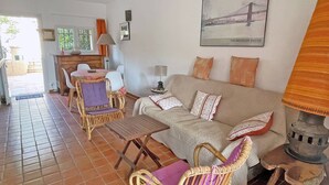A living room with a sofa, chairs, a small table, and a lamp. There is a door leading outside and a window with curtains. - House for 4 people - Sea view - Swimming pool - Air conditioning - WiFi - Near beach - Sainte Maxime (STE MAXIME)