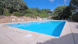 A rectangular swimming pool with a clear blue water surface, surrounded by a paved deck. There are white plastic chairs along the poolside, and a stone wall with greenery and trees in the background. - House for 4 people - Sea view - Swimming pool - Air conditioning - WiFi - Near beach - Sainte Maxime (STE MAXIME)