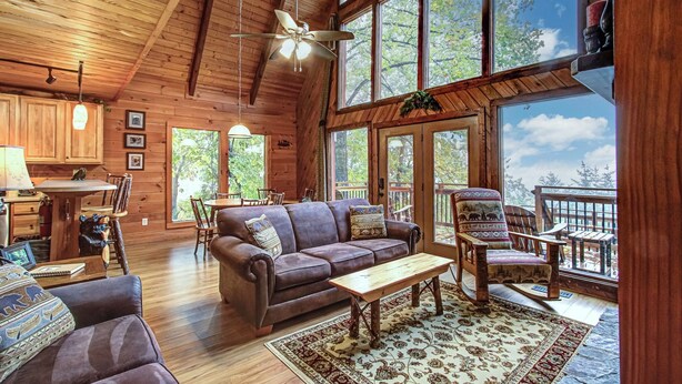 A spacious cabin with a high ceiling, wooden walls, and large windows offering a view of the outdoors. - Where Mountain views and quiet moments come naturally, it’s s’more than enough (Sevierville)