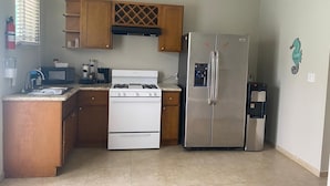 Cocina compacta con estufa, microondas, refrigerador y armarios de madera.