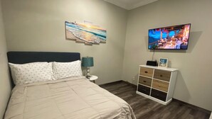 Un dormitorio con cama, mesita de noche, televisor y cómoda.