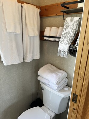 Ein kleines Badezimmer mit Toilette, Waschbecken und einem Regal für Handtücher.