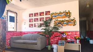 Una habitación acogedora con pared de ladrillo rojo, un sofá gris, una planta grande en maceta y una pared decorada con menús de comida enmarcados.