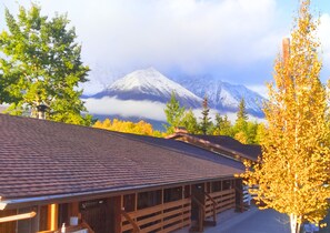 A wooden cabin with a sloped roof, surrounded by autumn foliage and a mountain in the background. - Cozy Corner Motel & Restaurant (Haines Junction)