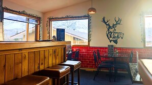 Interior de restaurante con cabinas de madera, paredes de ladrillo rojo y una decoración de cabeza de venado.