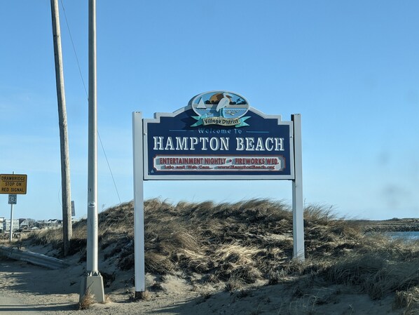 Un panneau d’accueil pour Hampton Beach, avec une plage et des dunes en arrière-plan.
