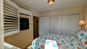 A bedroom with a bed, a TV mounted on a wall, a wardrobe, and a lamp.