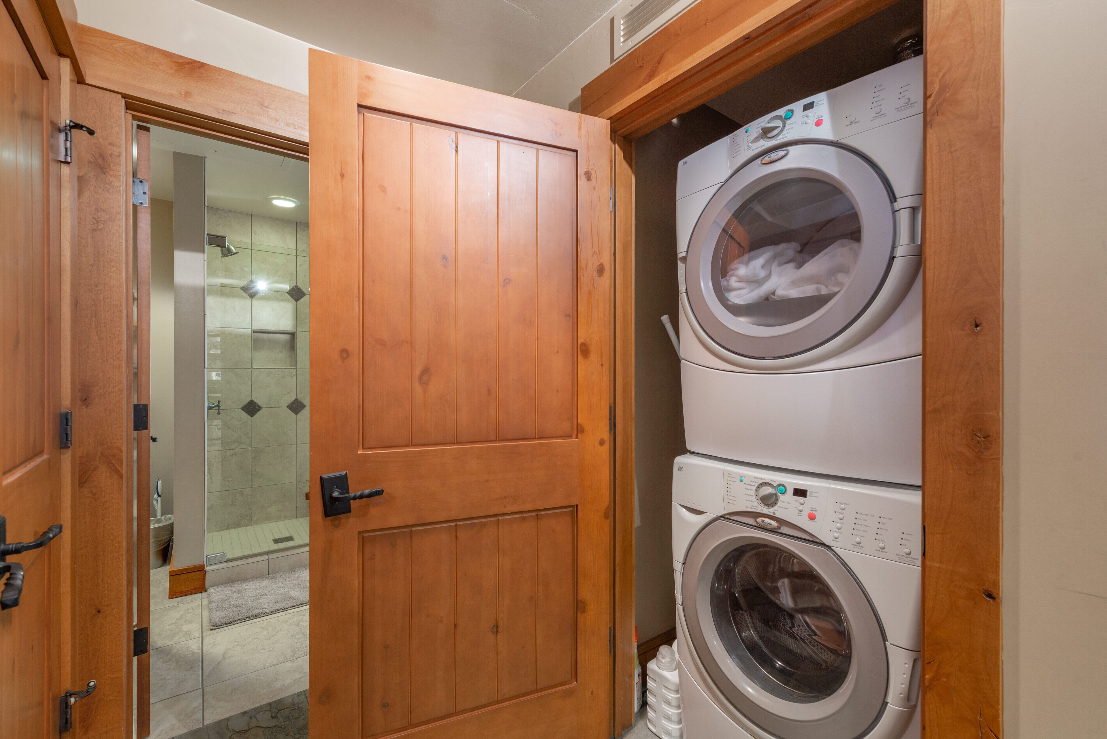 Una sala de lavandería con una puerta de madera, una lavadora y una secadora.
