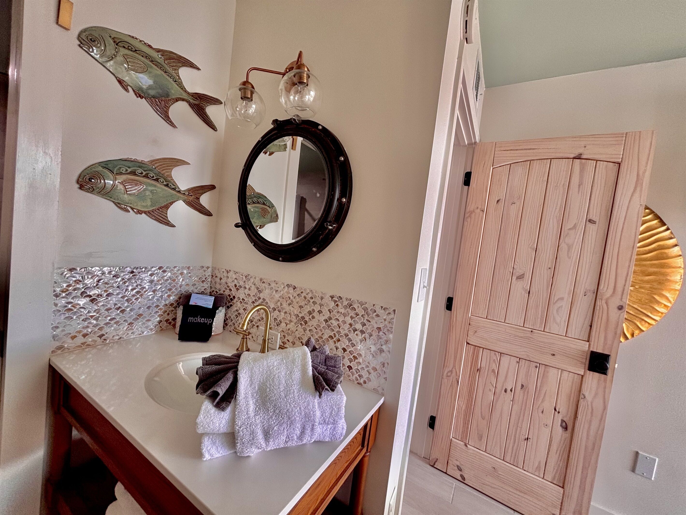 A bathroom with a sink, mirror, and decorative fish wall art.
