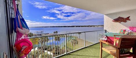 A balcony with a view of a beach and a tennis court.